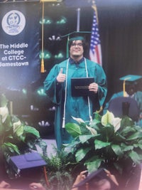 a woman in a graduation gown is holding her diploma